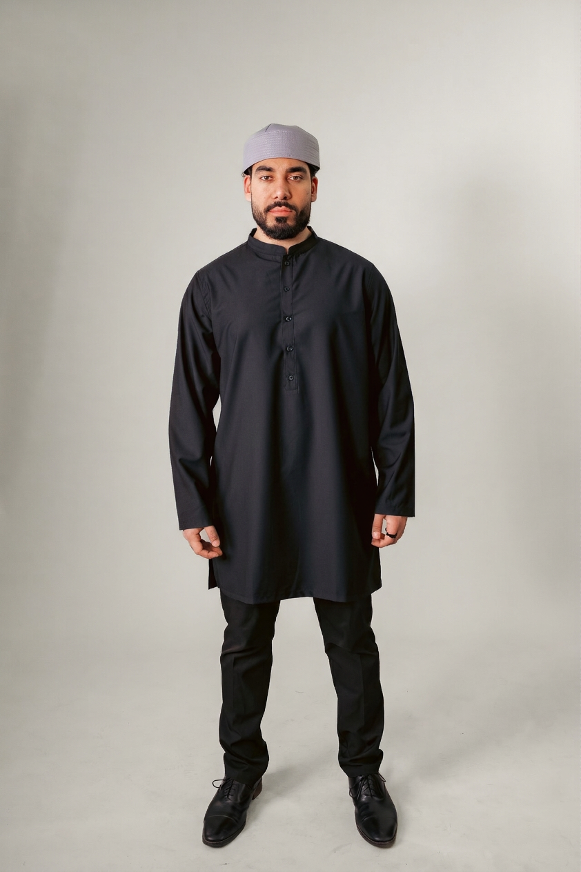 Man in navy traditional attire with hood, holding a beaded necklace, against a white background.