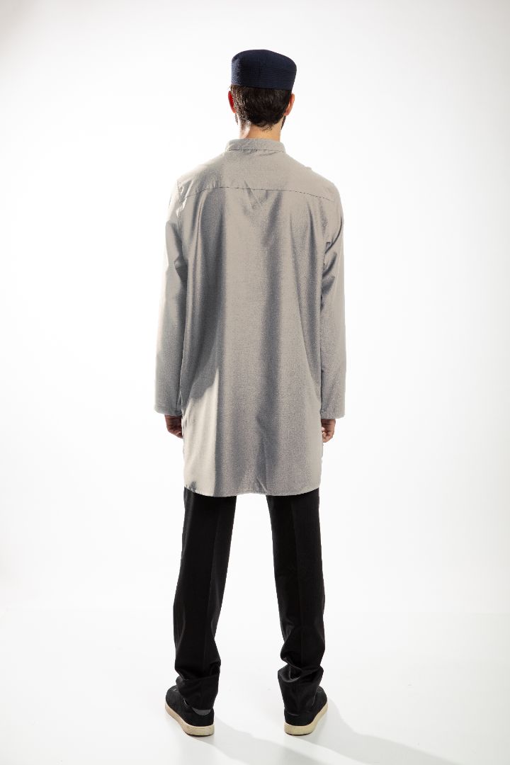 A person in a dark hooded robe, holding a string of beads, standing with back turned.