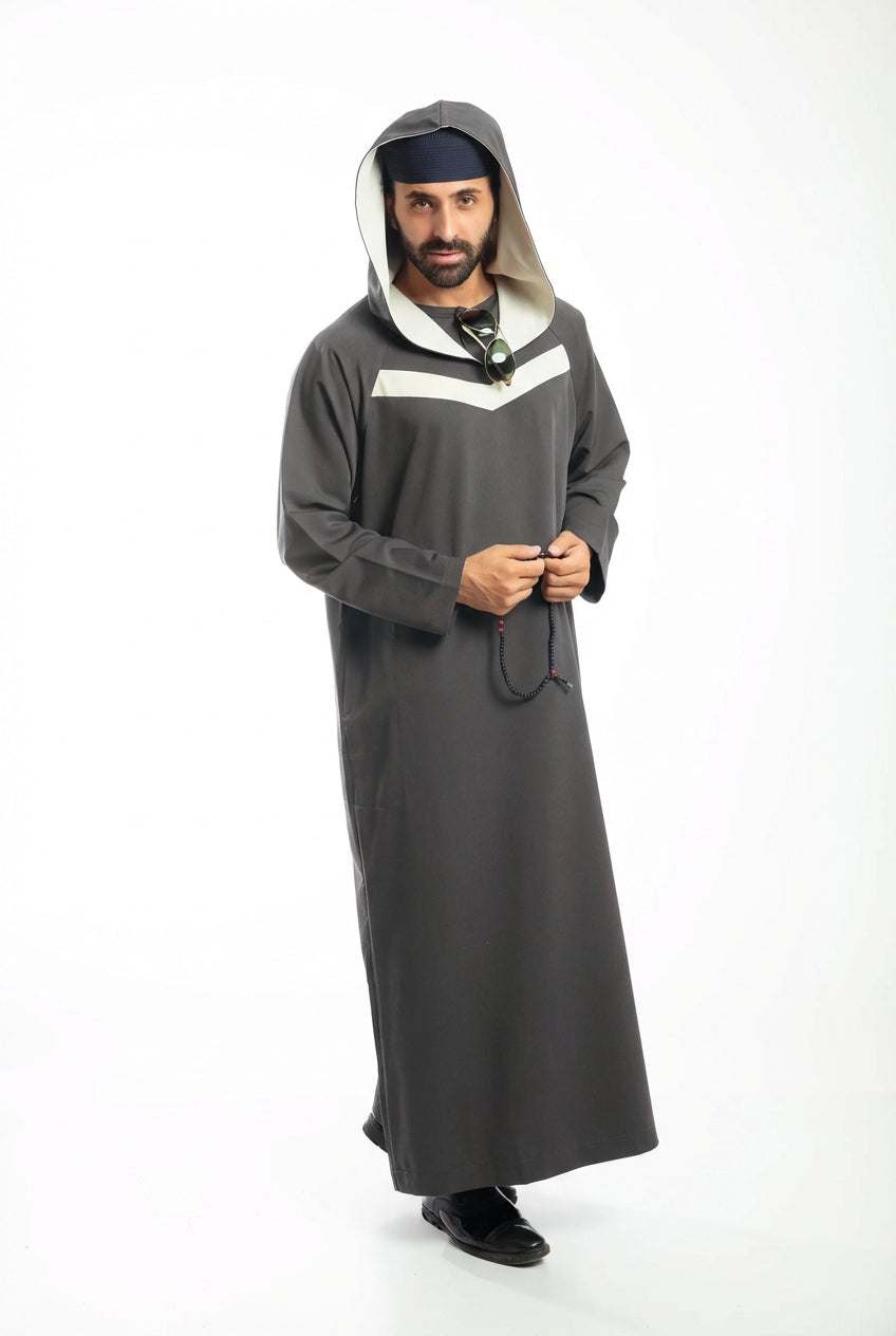 Man in navy traditional attire with hood, holding a beaded necklace, against a white background.