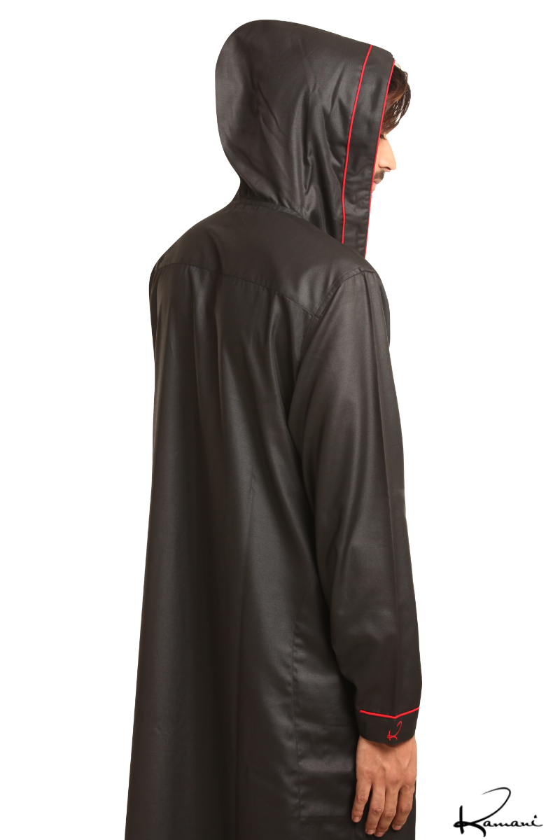 Man in a blue hooded robe holding glasses and a black bag against a white background.